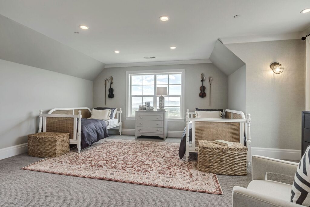 A cozy bedroom featuring two neatly made beds and a soft rug on the floor, creating a welcoming atmosphere.