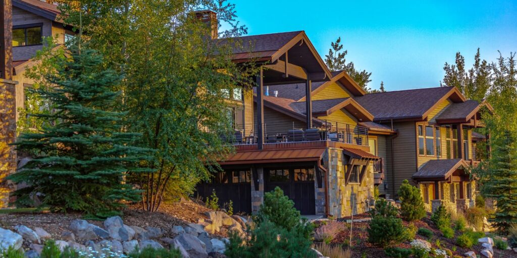 A large luxury home in Utah featuring a stone wall and an elegant driveway, showcasing upscale living in a serene environment.