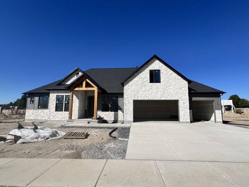 A house under construction featuring a garage and a driveway, showcasing the building process and materials used.