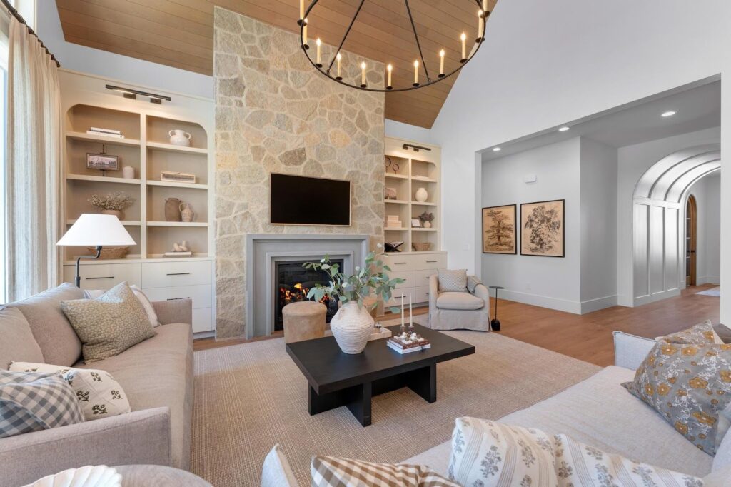 A cozy living room with a stone fireplace and an elegant chandelier, creating warmth