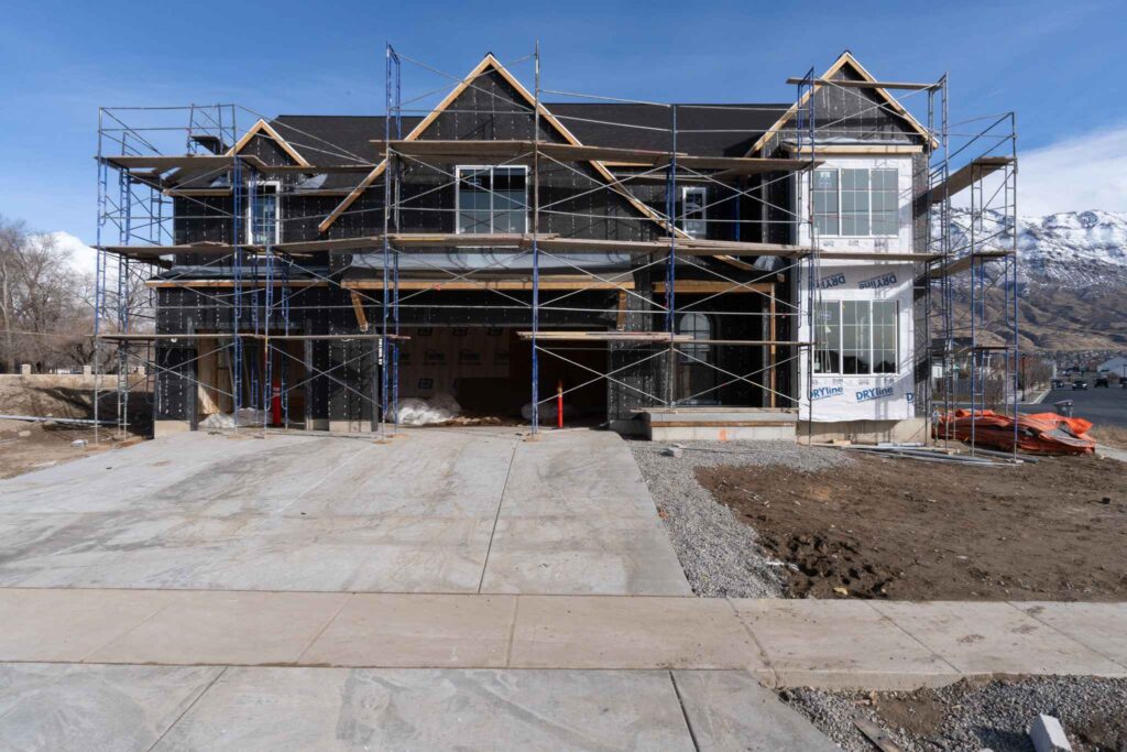 A house under construction with scaffolding, set against a scenic mountain backdrop, showcasing Patterson Homes' project.