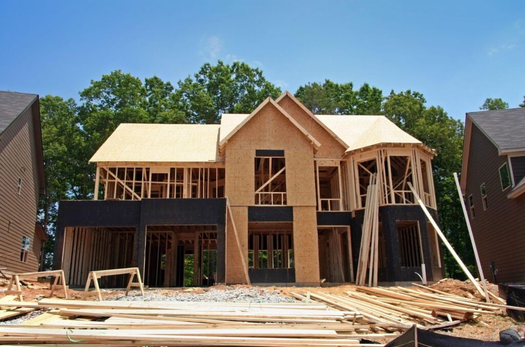 A house under construction with exposed wooden framing and scaffolding