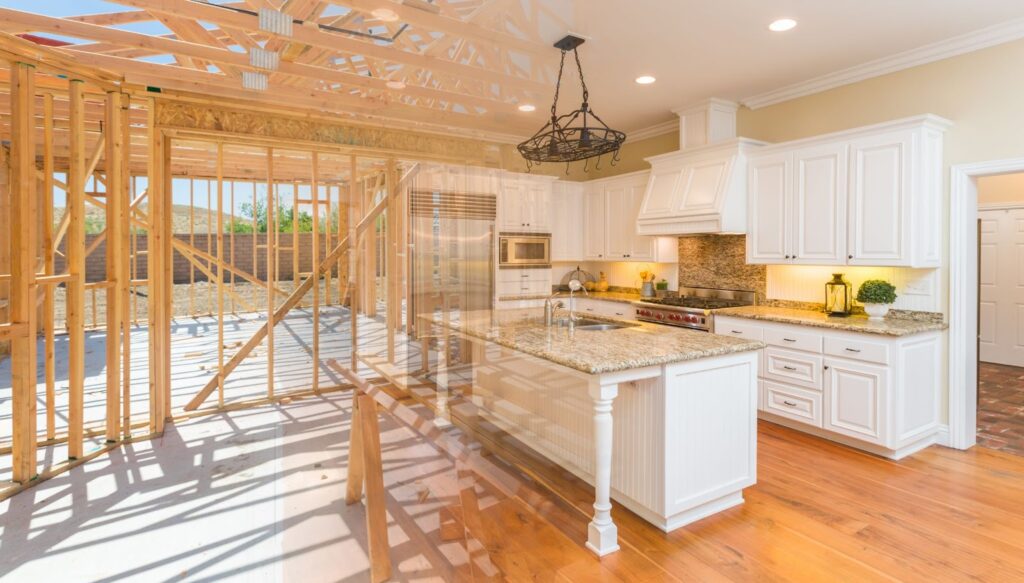 A split image showing a kitchen under construction with wooden framing on the left and the same kitchen completed on the right, featuring white cabinets, granite countertops, and hardwood floors.