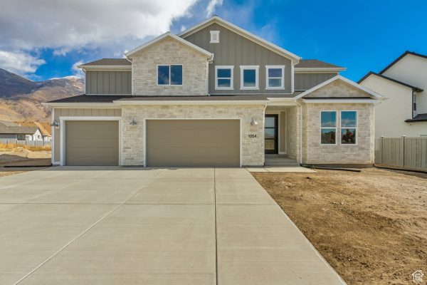 A charming residence featuring a driveway and garage, nestled in front of majestic mountains.